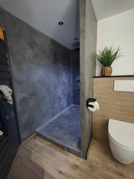 Revêtement en mortier minéral bi-composant AD Lucem, appliqué manuellement pour un rendu minéral lisse et nuancé, sur support placo sur le sol et murs d'une douche à Offlanges proche de Dole dans le Jura-BR HOME