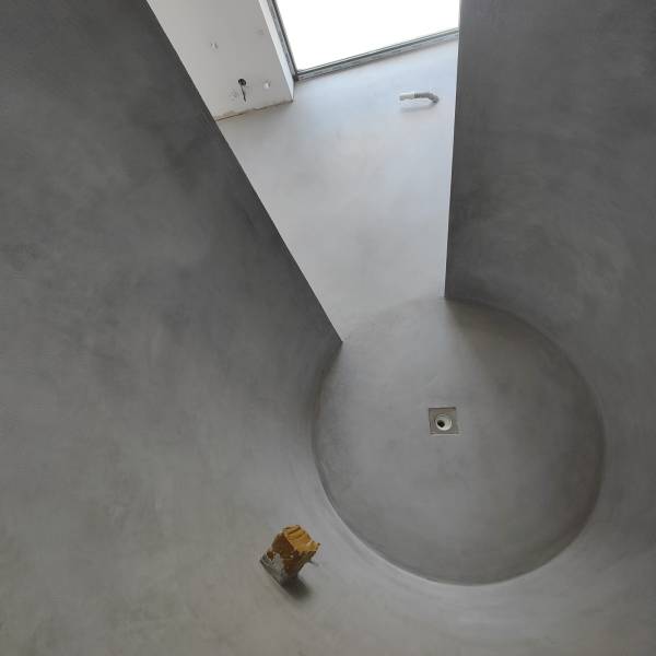 Revêtement minéral en béton ciré taloché à la finition mat, dans une salle de bain, au projet de réalisation technique et atypique à Besançon dans le Doubs.