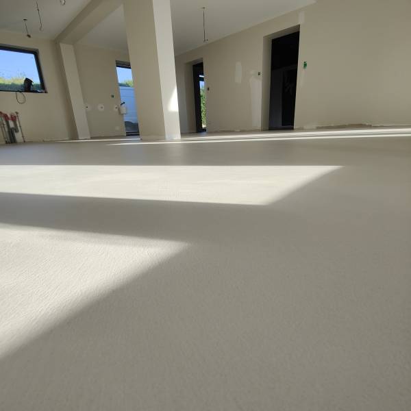 Application sur chape ciment d'un revêtement de sol en béton ciré taloché minéral aux nuances légeres, aspect contemporain et minimaliste épuré dans une cuisine, salle à manger, salon, entrée à Besançon dans le Doubs- BR HOME